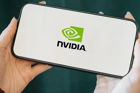 Close-up of a smartphone held in hands displaying the NVIDIA logo on the screen. Stock Photos