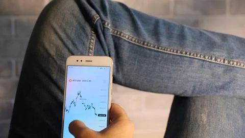 Close-up on the smartphone screen graph of the value of the cryptocurrency Bi Stock Photos