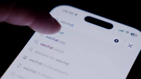 Close-up of a smartphone screen showing the WeChat app being searched and Stock Footage 337241488