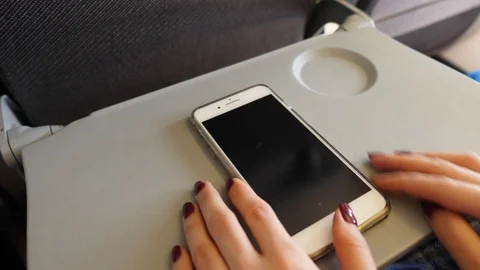 Close up smartphone on tilt table of airliner, woman scroll once and turn off Stock Footage