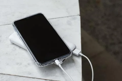 Close up of smartphone in transparent case connected to white portable charge Stock Photos