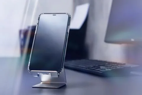 Close-up of a smartphone with a transparent case sits on a metal stand on a.. Stock Photos