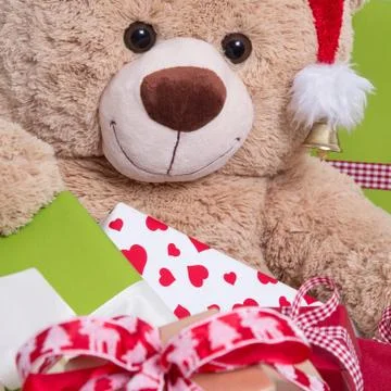 Close up of smiley teddy bear with gift boxes and christmas hat Stock Photos