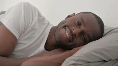 Close up of Smiling African Man Lying on Side in Bed Stock Footage 287904117