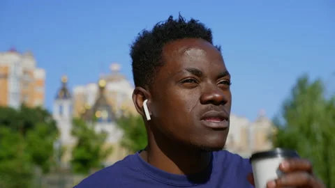 Close up smiling afro-american man wearing wireless earphones drinks coffee tea Stock Footage 159364285