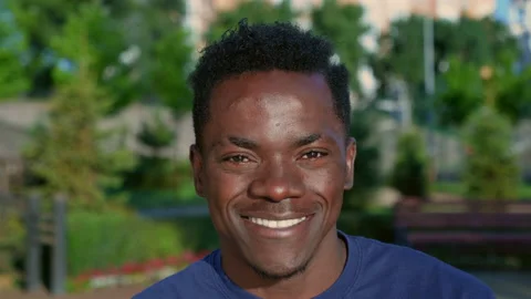 Close up smiling afro-american man looks camera on background park in summer Stock Footage 159811533
