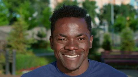Close up smiling afro-american man looks camera on background park in summer Stock Footage 160854310