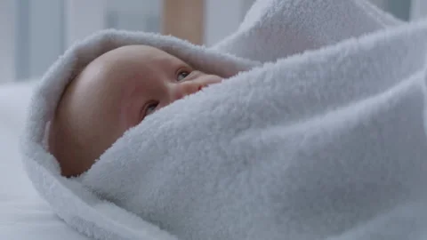 Close-up of smiling baby lying in bed on towel after bath Stock Footage 306009839