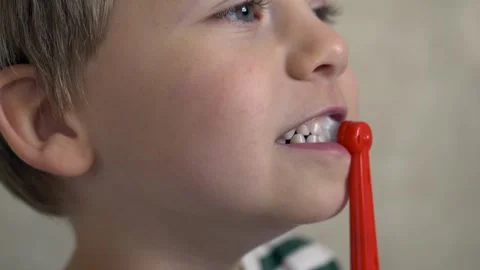 Close-up of smiling boy holding red electric toothbrush during tooth-cleaning Stock Footage 322173139