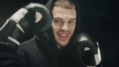 Close-up of smiling brutal strong man with nose piercing in dark hoodie throwing Stock-Footage 157075790