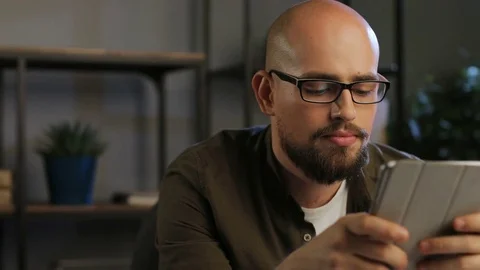 Close up smiling businessman in glasses using tablet computer while working in Stock Footage 81112356