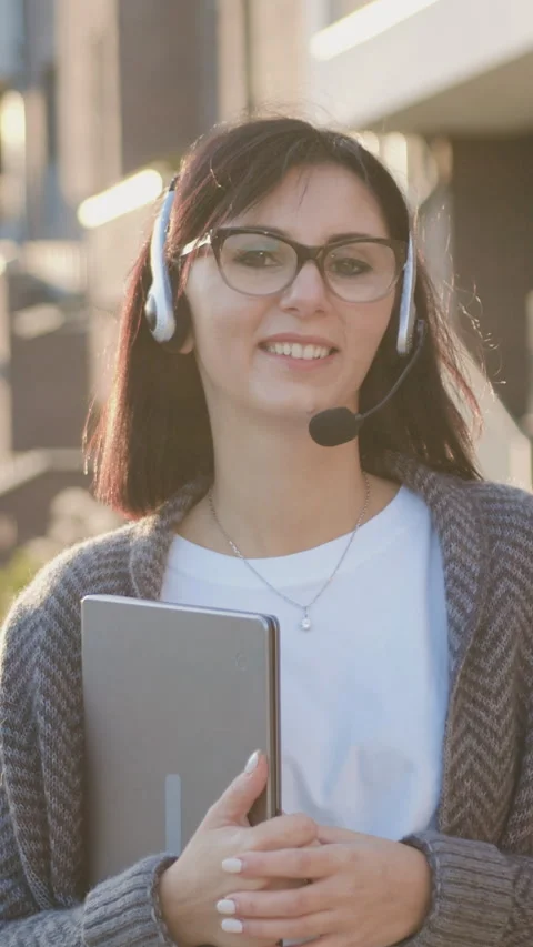 Close-up of smiling cute caucasian young woman with headset and laptop device lo Stock Footage 328594849