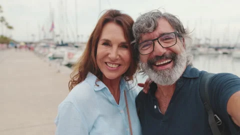 Close-up of smiling elderly couple making video call, streaming while standing Stock Footage 255965210