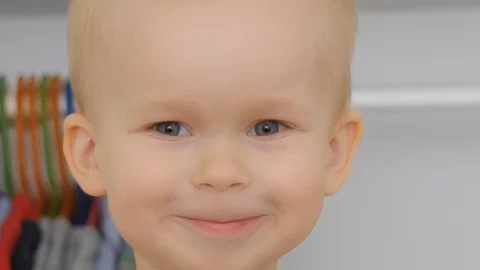 Close up smiling face of adorable cute little boy posing at clothes cabinet Stock Footage 129681333