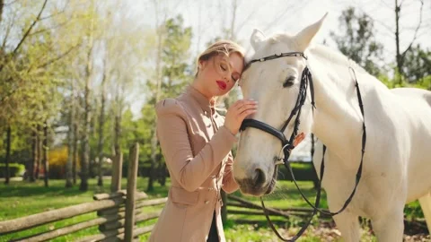 Close-up smiling face red lips happy woman with white horse hand touching muzzle Stock Footage 307213250