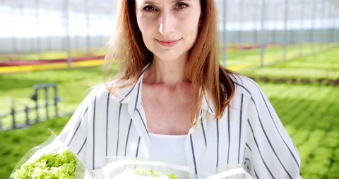 Close up of smiling female farm worker in casual wear posing with basket of Stock Footage 196813161
