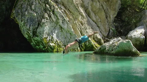 CLOSE UP: Smiling man jumping head first into stunning clear water and swimming Stock Footage