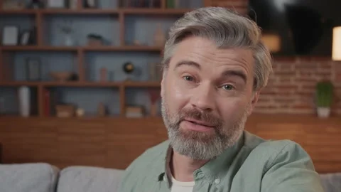 Close up smiling man making selfie or video call while sitting at home on sofa Vídeos de archivo 220202081