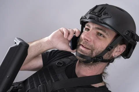 Close up of a smiling man talking over the phone in his airsoft equipment Stock Photos