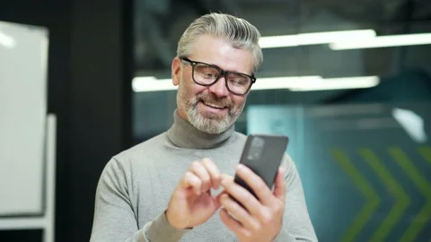 Close up of smiling mature gray haired bearded businessman texting online Stock Footage 232581710
