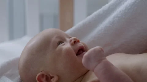 Close-up, smiling newborn baby lying in bed wrapped in towel, after bath Stock Footage 306006087