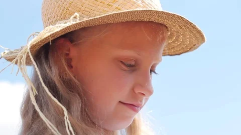 Close-up of smiling nice child wearing straw hat looking down. Portrait of Stock Footage 99704551