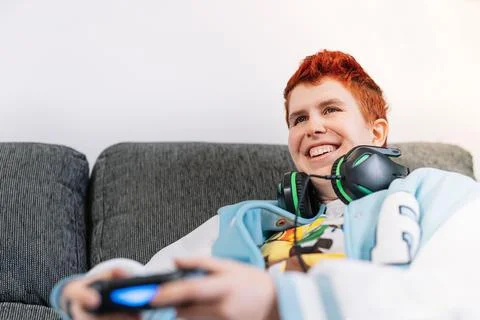 Close-up of a smiling non-binary person playing video games in the living room Stock Photos