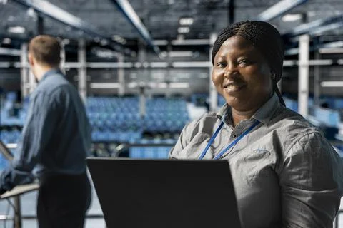 Close up of smiling worker in server farm next to colleague upgrading hardware Stock Photos