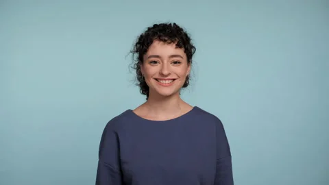 Close up smiling young curly woman in blue sweater posing looking camera Stock Footage 234184053