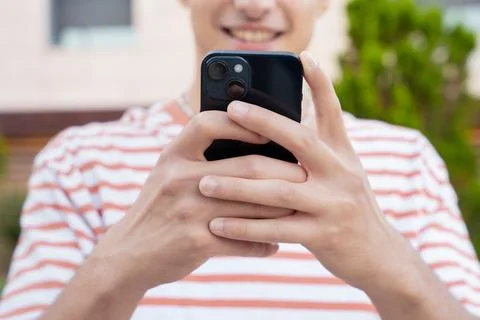 Close-up of smiling young man using smartphone app outdoors. Stock Photos
