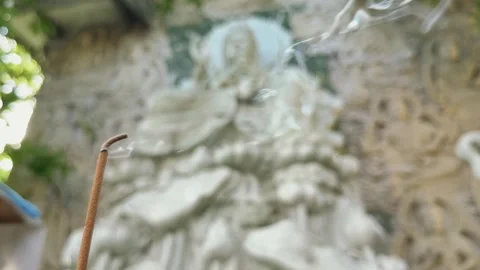 Close up of smoke from Incense stick and blurred Stone Buddhist Relief in the Stock Footage 340118778