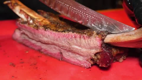 Close-up of Smoked Beef Ribs Being Sliced on a Red Cutting Board Vídeos de archivo 332813994