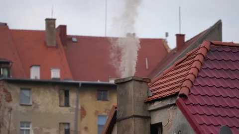 Close-up smoky chimneys on old bricks buildings with red roofs in the city. Video stock 235626574