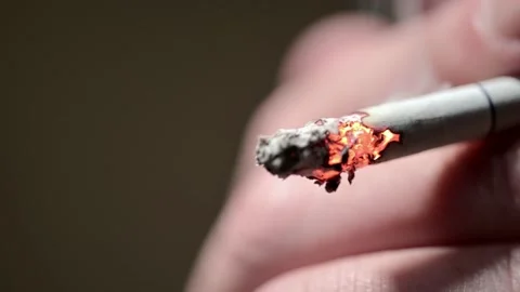 Close-up of a smoldering cigarette during a puff. Hand holds a smoking Stock-Footage 154003922