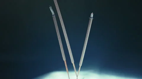 Close up of smoldering incense, three sticks, white light from below Stock Footage 307749486