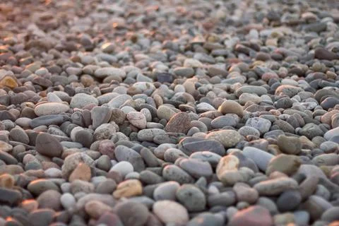 Close-up of smooth pebbles on a beach, bathed in soft evening light Stock Photos