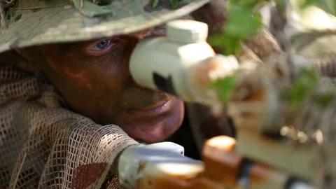 Close-up. The sniper looking through scope and reporting the situation by radio Stock Footage 127629229