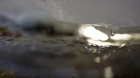 Close up of snow and ice dripping water drop into mountain stream slow motion Stock Footage 156047403
