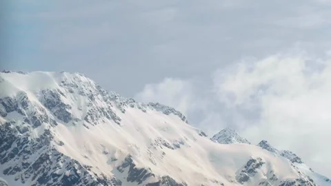 Close-up of snow-capped mountains shrouded in clouds and mist Stock Footage 260887635