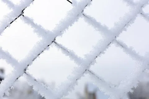 Close-up of snow covered mesh net with bright blue sky in background confining Stock Photos