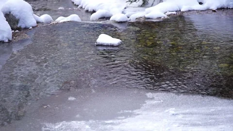 Close-up of snow-covered rocks in a partially frozen creek Stock Footage 310230059