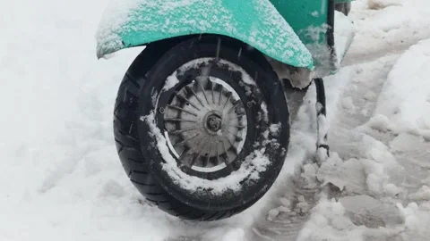 Close-up of a snow-covered scooter wheel and tire in winter slush Stock Footage 331977331