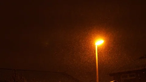 Close-up of snow falling in front UK yellow uk street light, 4k Video stock 87271742