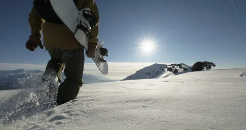 Close-up snowboarder walking in deep snow to the mountain peak, extreme off Stock Footage 256105339