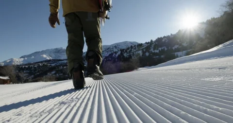 Close-up snowboarder walking on an empty ski slope with snowboard in his hand in Stock Footage 258188966