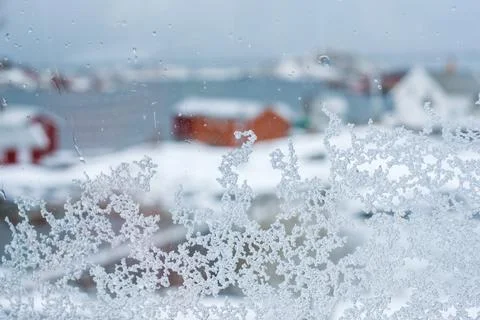 Close-up snowflake on window with blurred house in winter Stock Photos