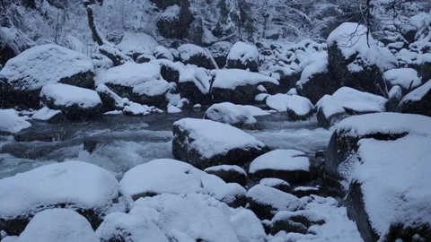 Close-Up of Snowy Mountain River Flowing Through Winter Landscape | 4K Stock Footage 311945421