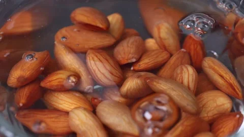 Close up of soaking almonds in water in a glass bowl Stock Footage 334728818