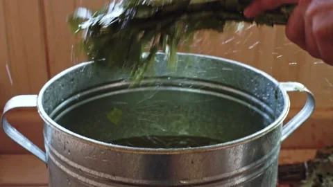 Close-up of soaking a bath broom in a metal basin. Bath juniper broom Stock Footage 232269691