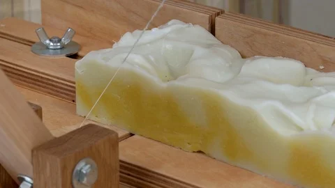 A close-up of a soap-cutting machine. A string cuts a rectangular piece Stock Footage 93012418